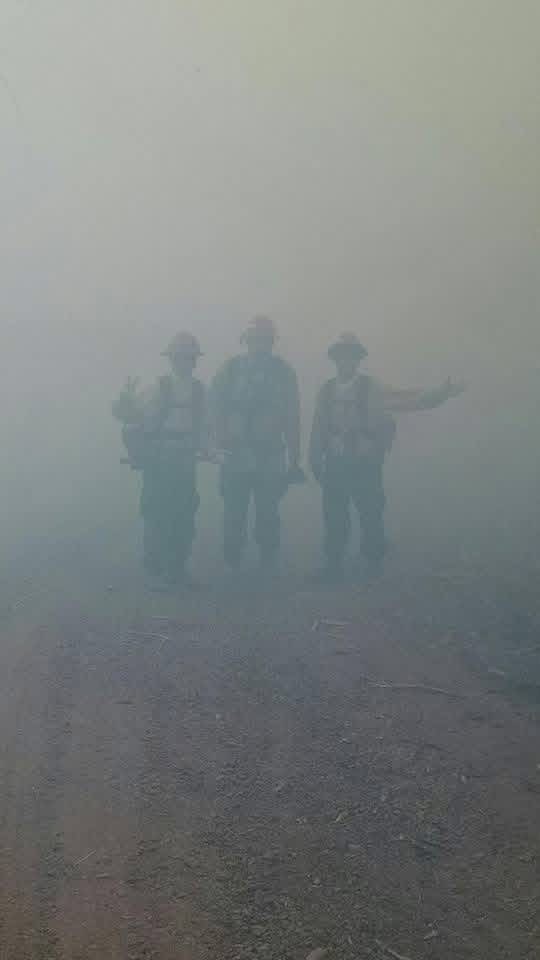 Three firefighters standing in heavy smoke